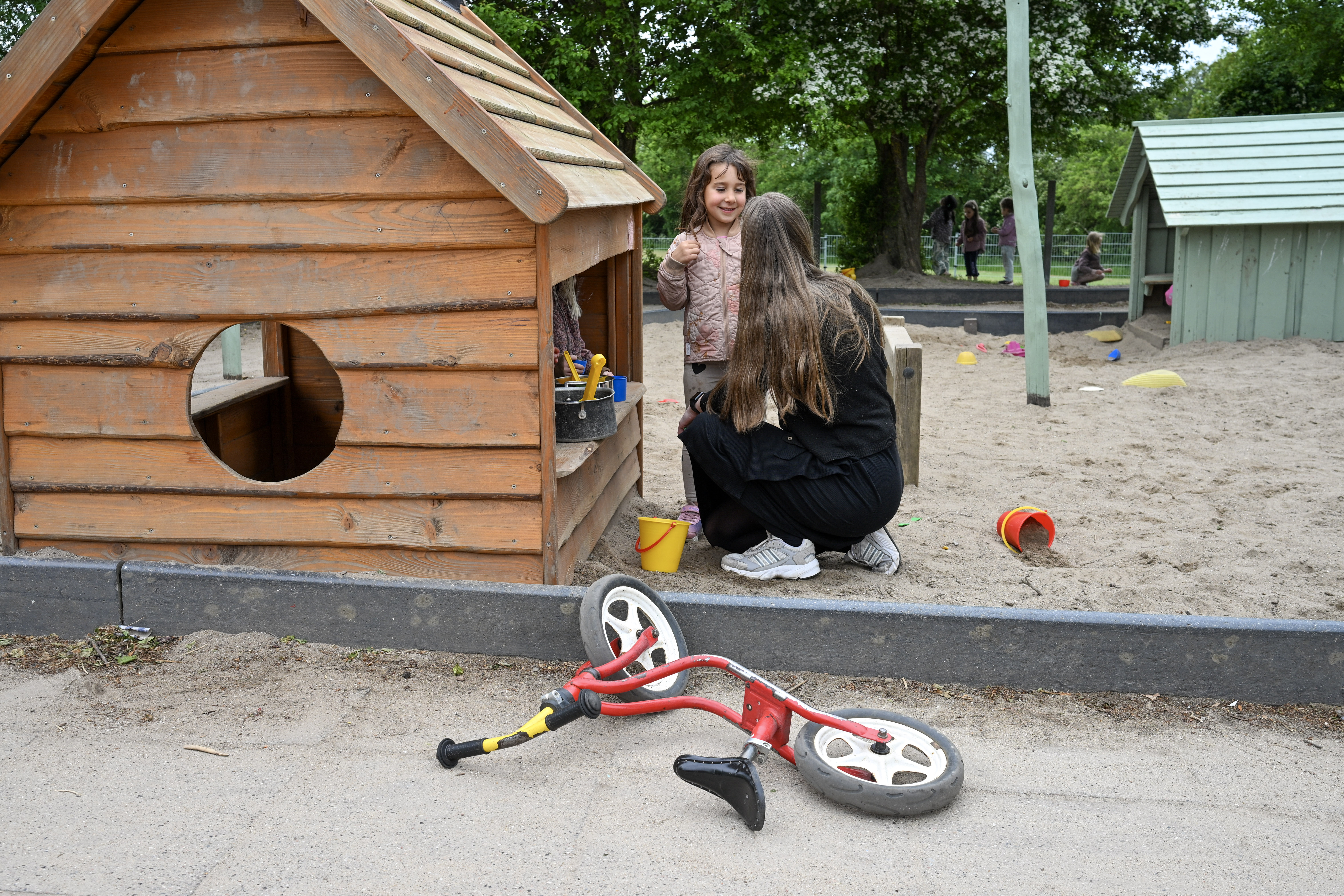 Voksen snakker med barn ved legehus
